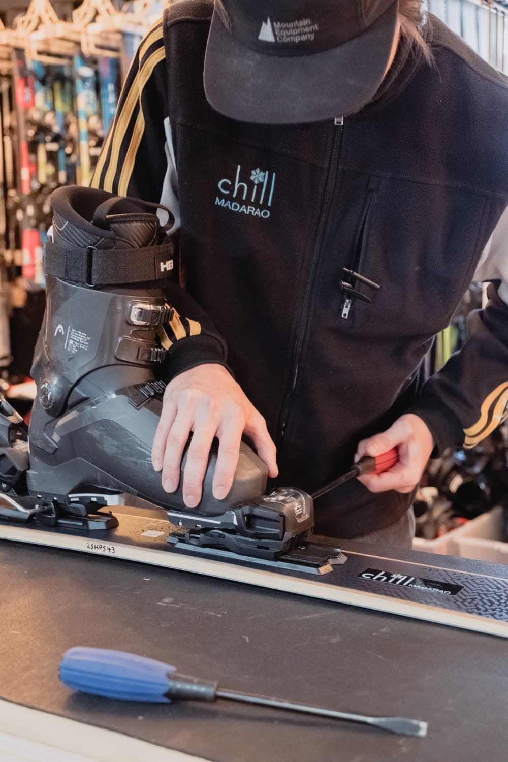 A Chill technician adjusting bindings to a ski boot on the workshop bench.